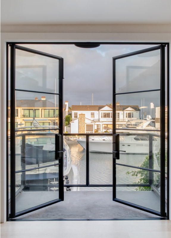 Black steel swing doors overlooking a marina